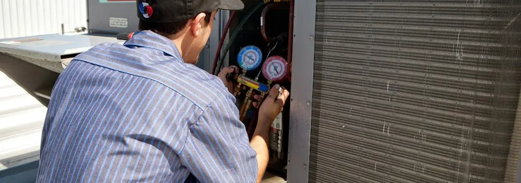 HVAC technician servicing a condenser unit in Pendleton